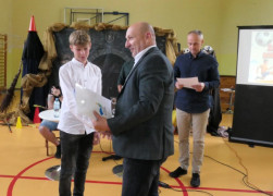 Mężczyzna wręcza dyplom chłopcu