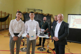 Dwaj chłopcy i mężczyzna. Jeden z chłopców trzyma w ręku dyplom 