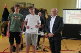 Dwaj chłopcy i mężczyzna. Jeden z nich trzyma w ręku dyplom 