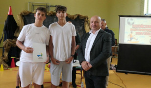 Dwaj chłopcy i mężczyzna. Jeden z chłopców trzyma w ręku dyplom 