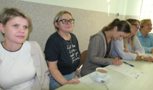 Kobiety siedzą obok siebie. Panie uczestniczą w szkoleniu. 