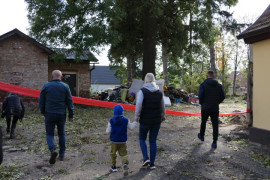 Grupa osób, zagrodzony teren, widoczny gruz