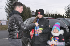 Dziewczyna, chłopak i mała dziewczynka. Chłopak wrzuca pieniądze do puszki WOŚP