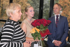Dwie kobiety i mężczyzna. Jedna z kobiet trzyma w dłoniach dwa bukiety róż