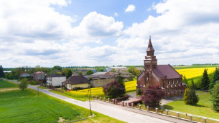 Kościół w Dziepółci w otoczeniu pół, na których kwitnie rzepak 