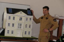 Strażak prezentujący edukacyjny dom 