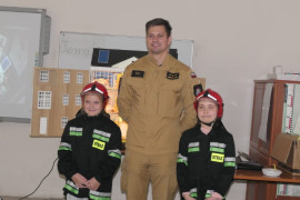 Uczennice PSP Strzałków w towarzystwie strażaka PSP Radomsko. Dziewczynki ubrane są w stroje strażackie 
